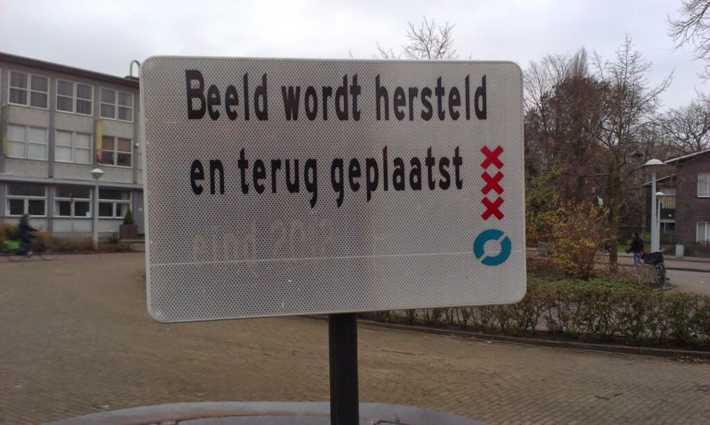 Bord in Amsterdam met de tekst: Beeld wordt hersteld en teruggeplaatst.