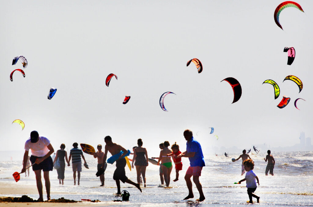 Diverse mensen op het strand vliegeren