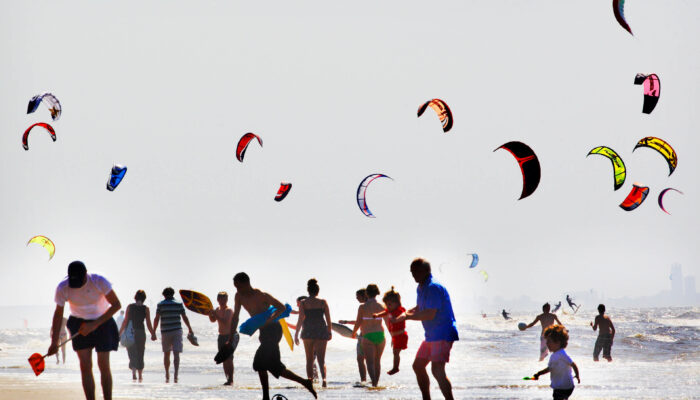 Diverse mensen op het strand vliegeren