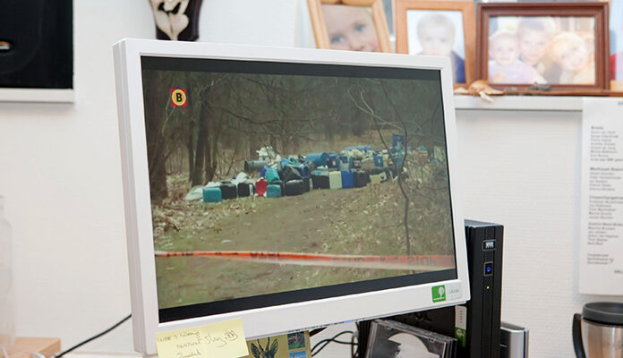 Op een computerscherm is een foto te zien van gedumpt drugsafval.