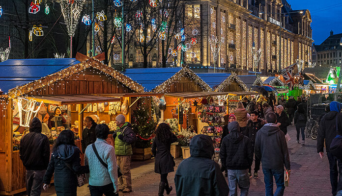 mensen lopen over een kerstmarkt op het Damrak in Amsterdam