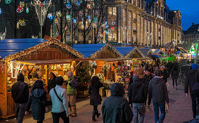 mensen lopen over een kerstmarkt op het Damrak in Amsterdam