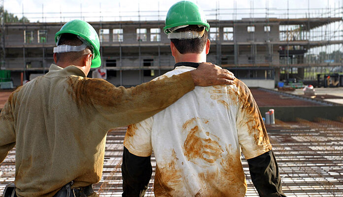 Twee bouwvakkers kijken gearmd naar bouwproject