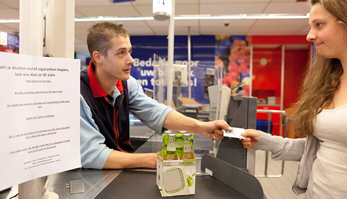 Kassamedewerker vraagt een ID aan een tiener die alcohol wil kopen.