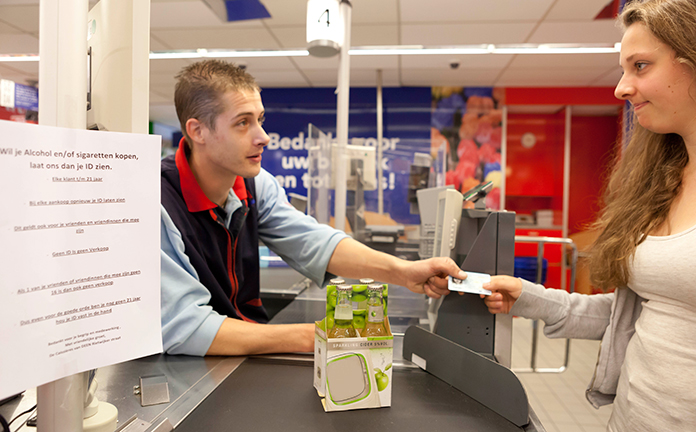Kassamedewerker vraagt een ID aan een tiener die alcohol wil kopen.