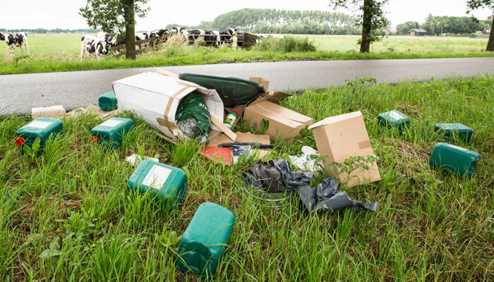 In een berm liggen diverse vaten met chemisch afval.