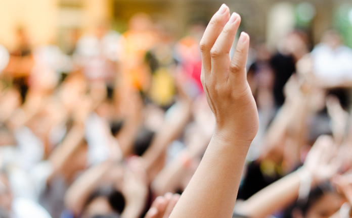 Iemand in zaal steekt hand op
