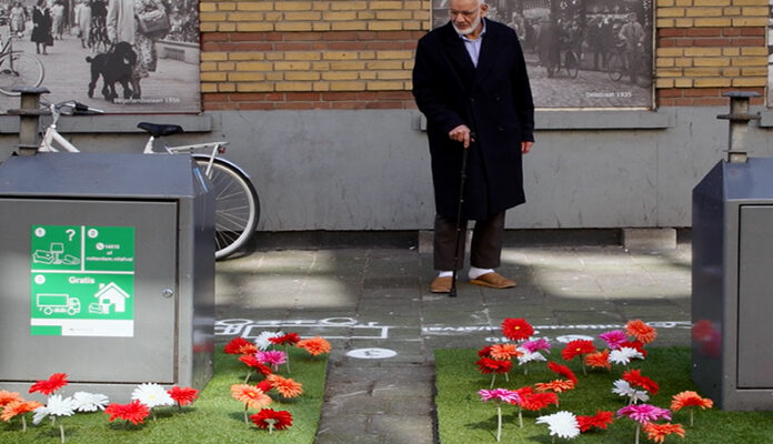 Man bekijkt fleurig bloemperkje om containers