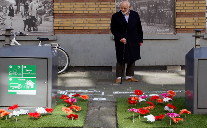 Man bekijkt fleurig bloemperkje om containers