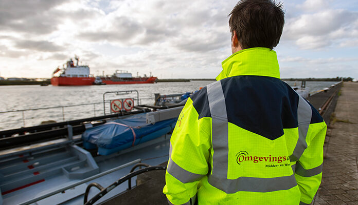 Professional van Omgevingsdienst kijkt naar schip