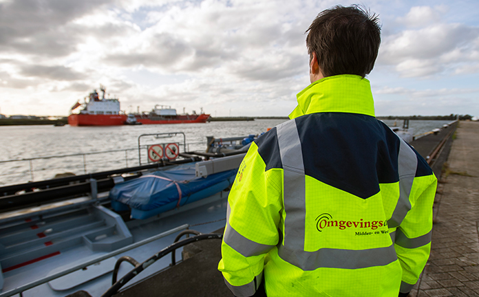 Professional van Omgevingsdienst kijkt naar schip