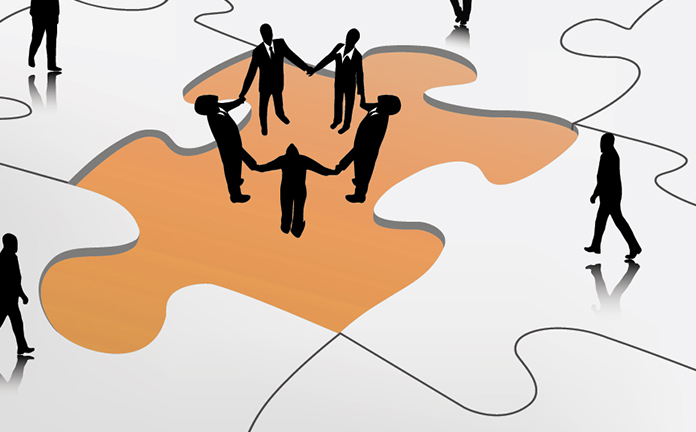 Vijf poppetjes houden elkaars hand vast in een cirkel en staan in een puzzelstukje