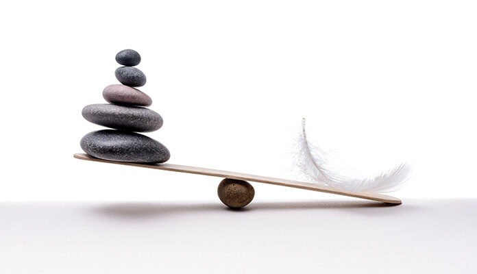 Weegschaal met aan de ene kant stenen en aan de andere kant een veertje