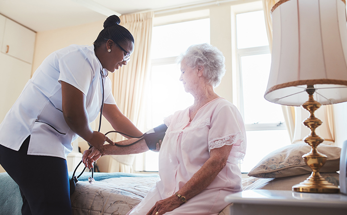 Verzorgende meet bloeddruk bij oudere dame