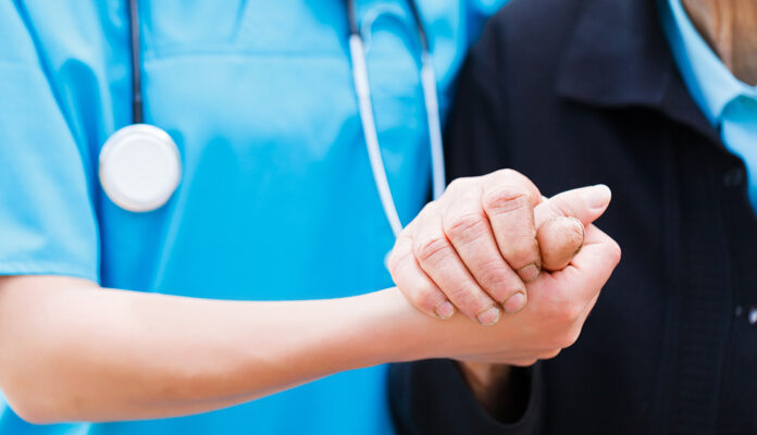 Verzorger houdt hand van oudere vast