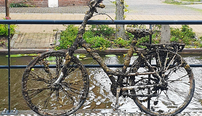 Fiets met kroos leunt tegen brug