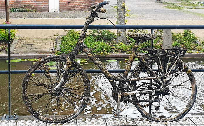 Fiets met kroos leunt tegen brug