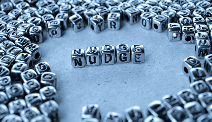 Zilveren kralen met letters waarmee het woord nudge is gevormd