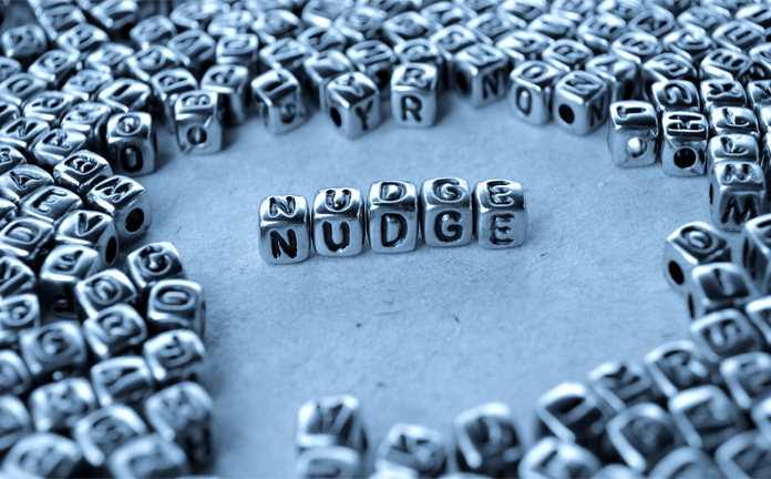 Zilveren kralen met letters waarmee het woord nudge is gevormd