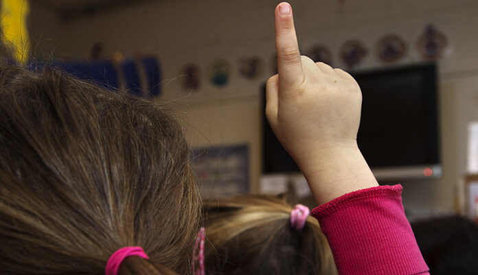 Kind steekt haar vinger op in de klas.