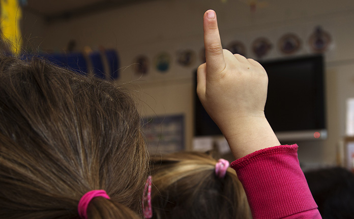 Kind steekt haar vinger op in de klas.