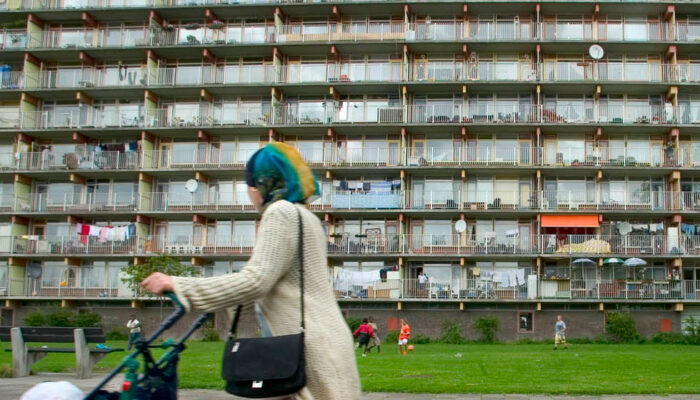 Voruw met kinderwagen loopt voor een flat in Gouda.