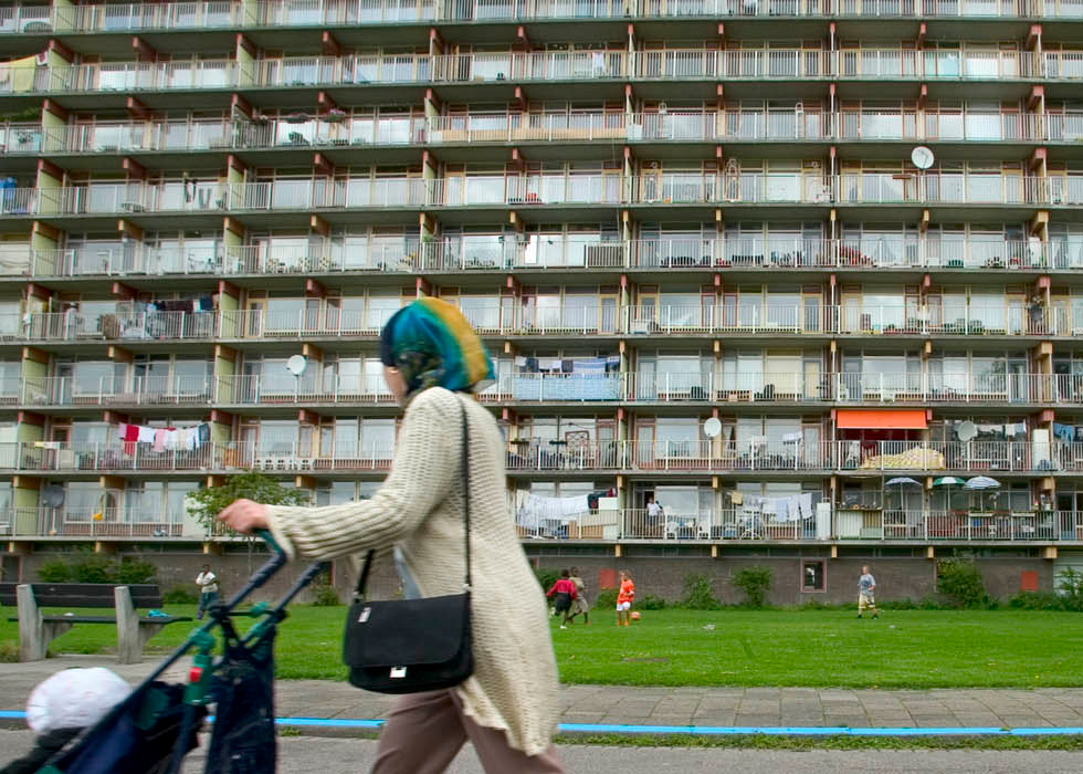 Voruw met kinderwagen loopt voor een flat in Gouda.