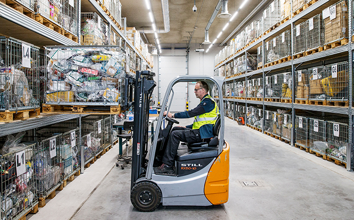 Douanemedewerker haalt met heftruck pallet met pakketjes uit stelling