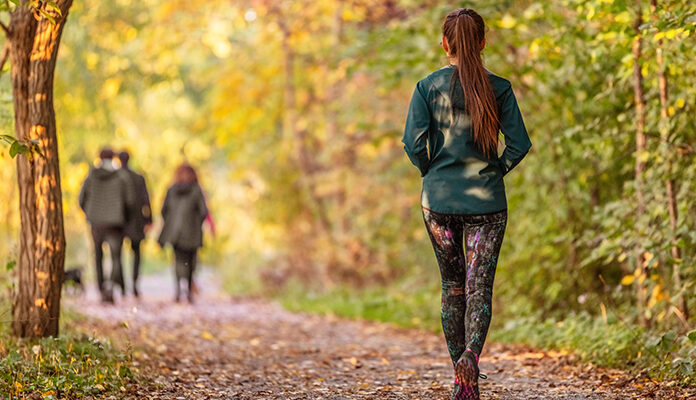 Vrouw loopt hard in bos. Voor haar lopen drie personen.