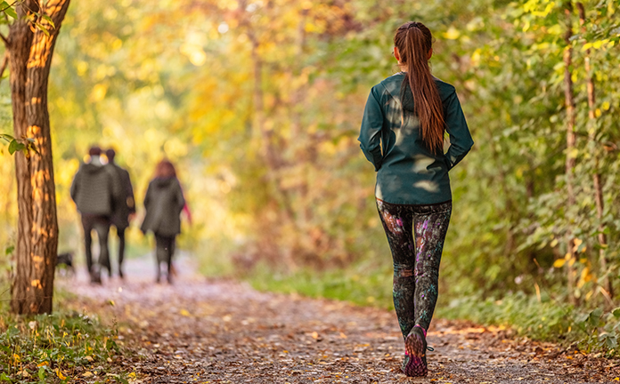 Vrouw loopt hard in bos. Voor haar lopen drie personen.