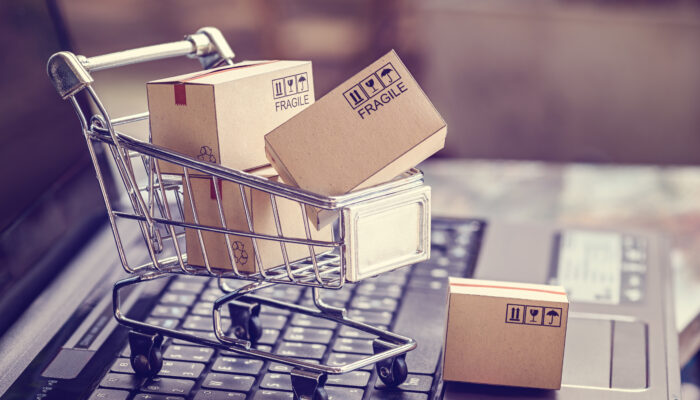 Laptop met daarop een klein winkelkarretje met dozen