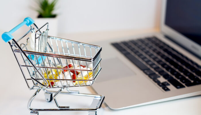 Winkelwagentje met medicijnen naast laptop