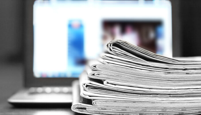 Stapel kranten met computerscherm