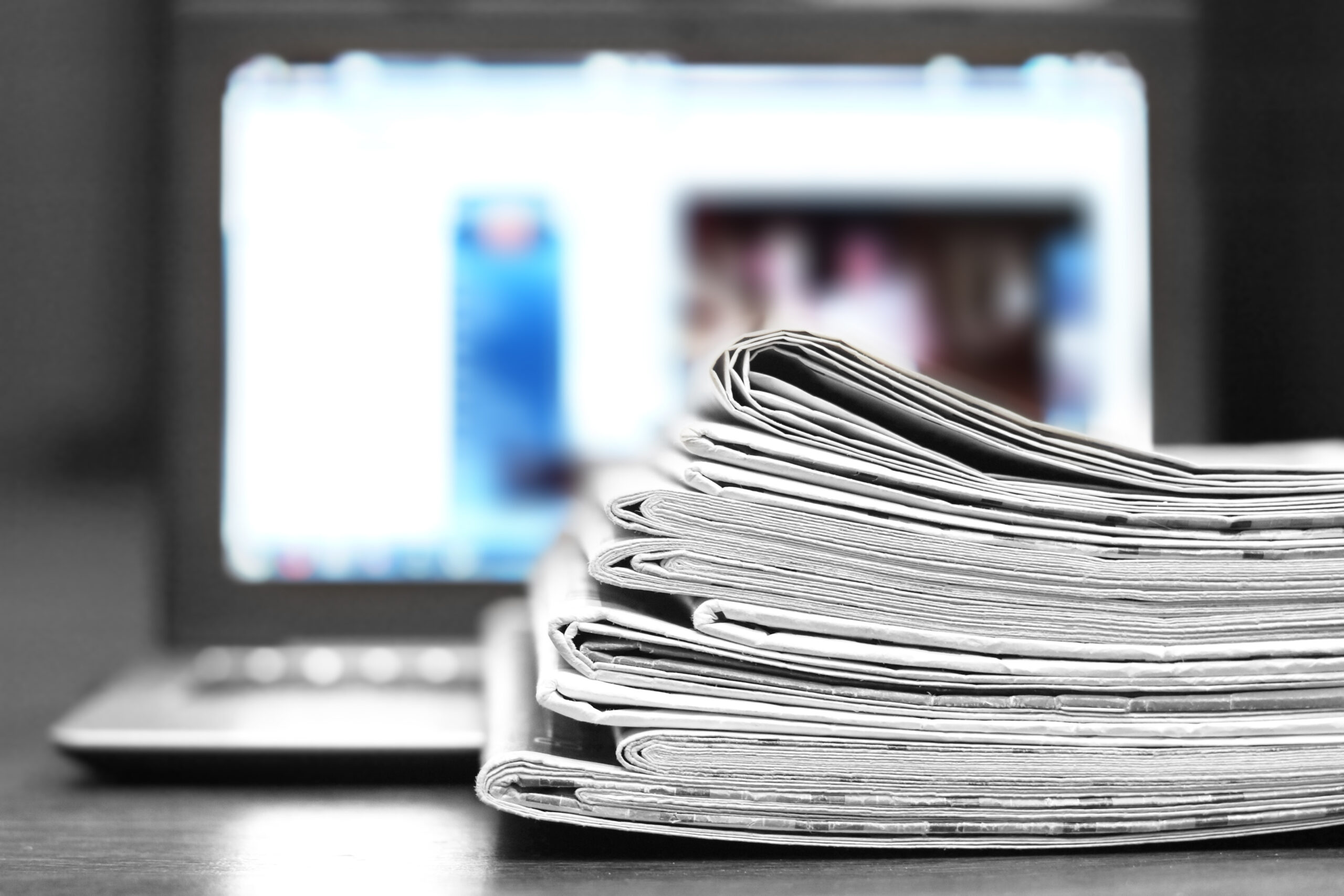 Stapel kranten met computerscherm