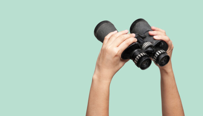 Iemand houdt verrekijker omhoog